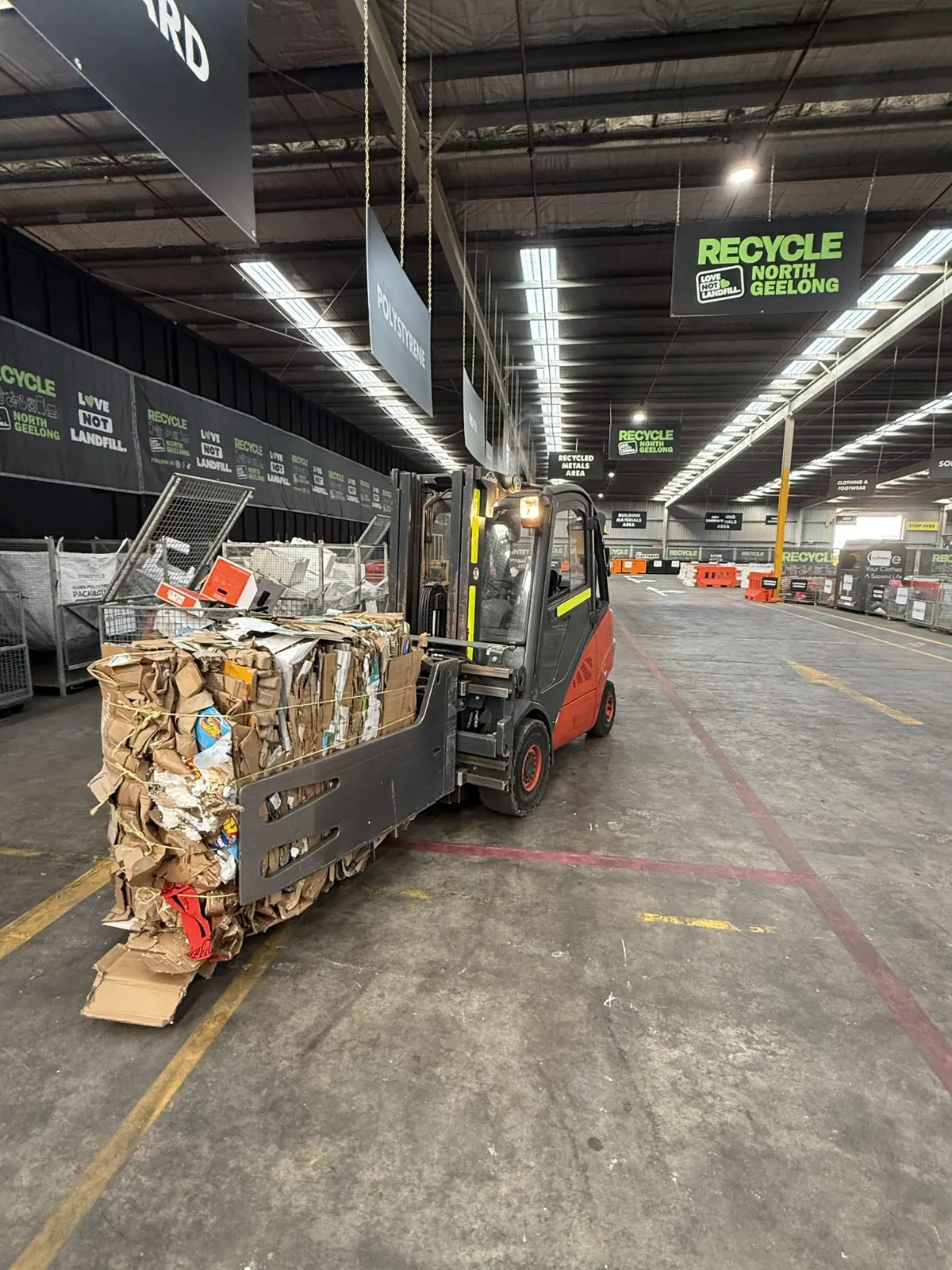 A forklift moving a baled block of cardboard down the hall