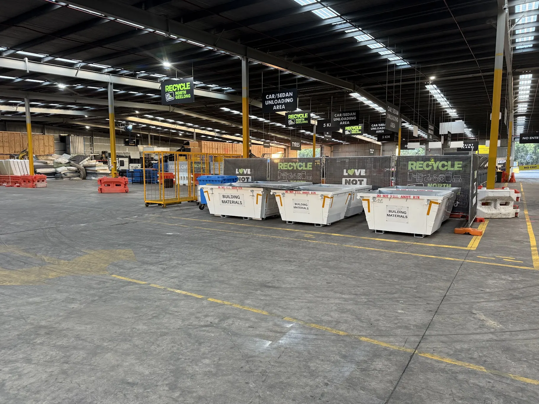 A long row of skips and cages under cover along the hall